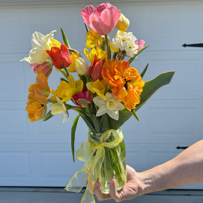 Bouquet of colorful flowers held by a person in front of a door.